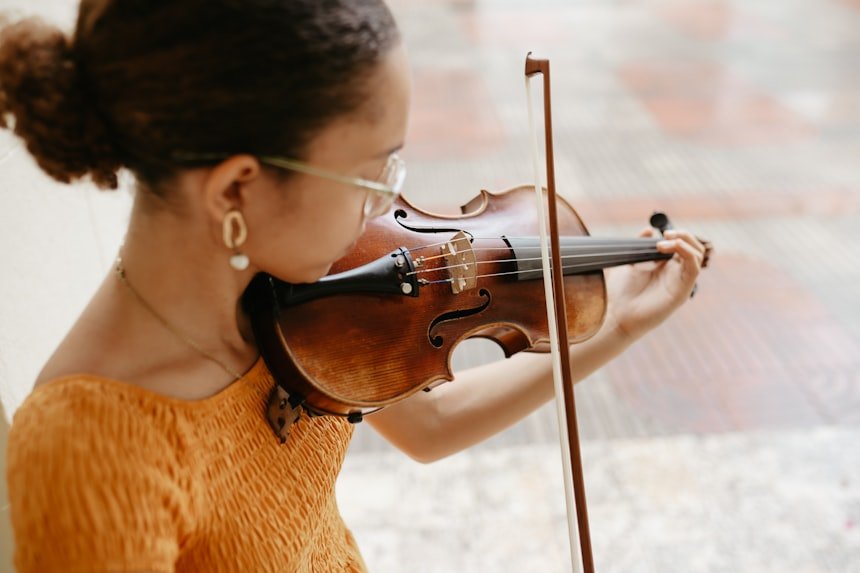 Woman in orange dress playing violin outdoors — advanced performance